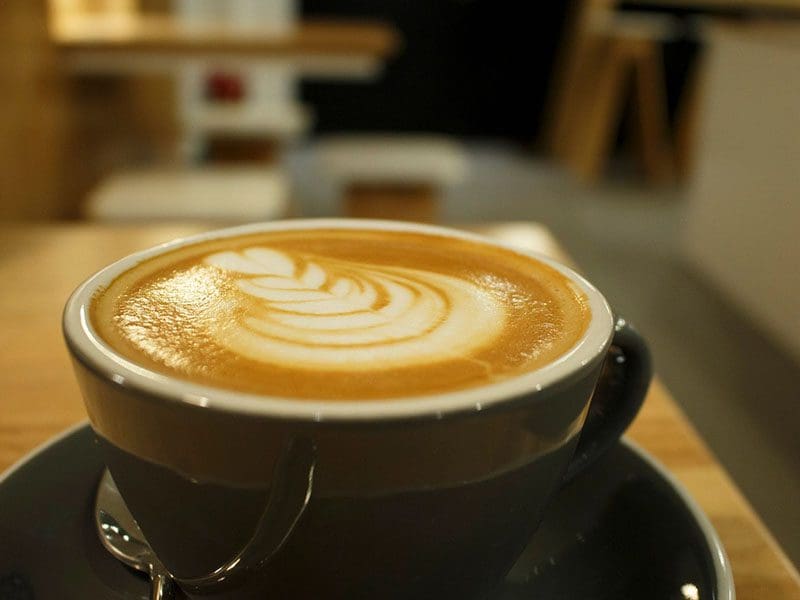 A cup of coffee with swirly cream on top.