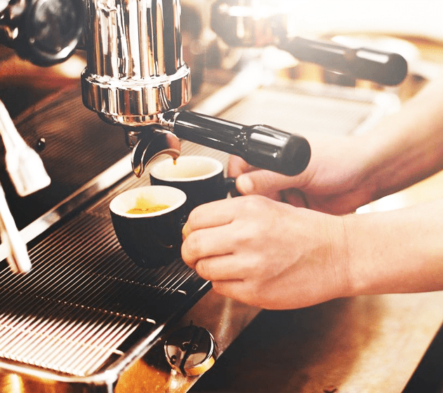 A person is making coffee in a cafe.